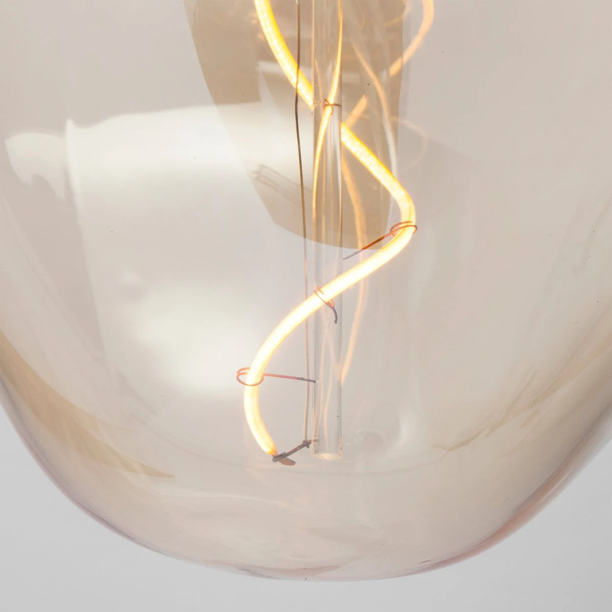 Close detail of a curved filament inside a sculptural glass bulb